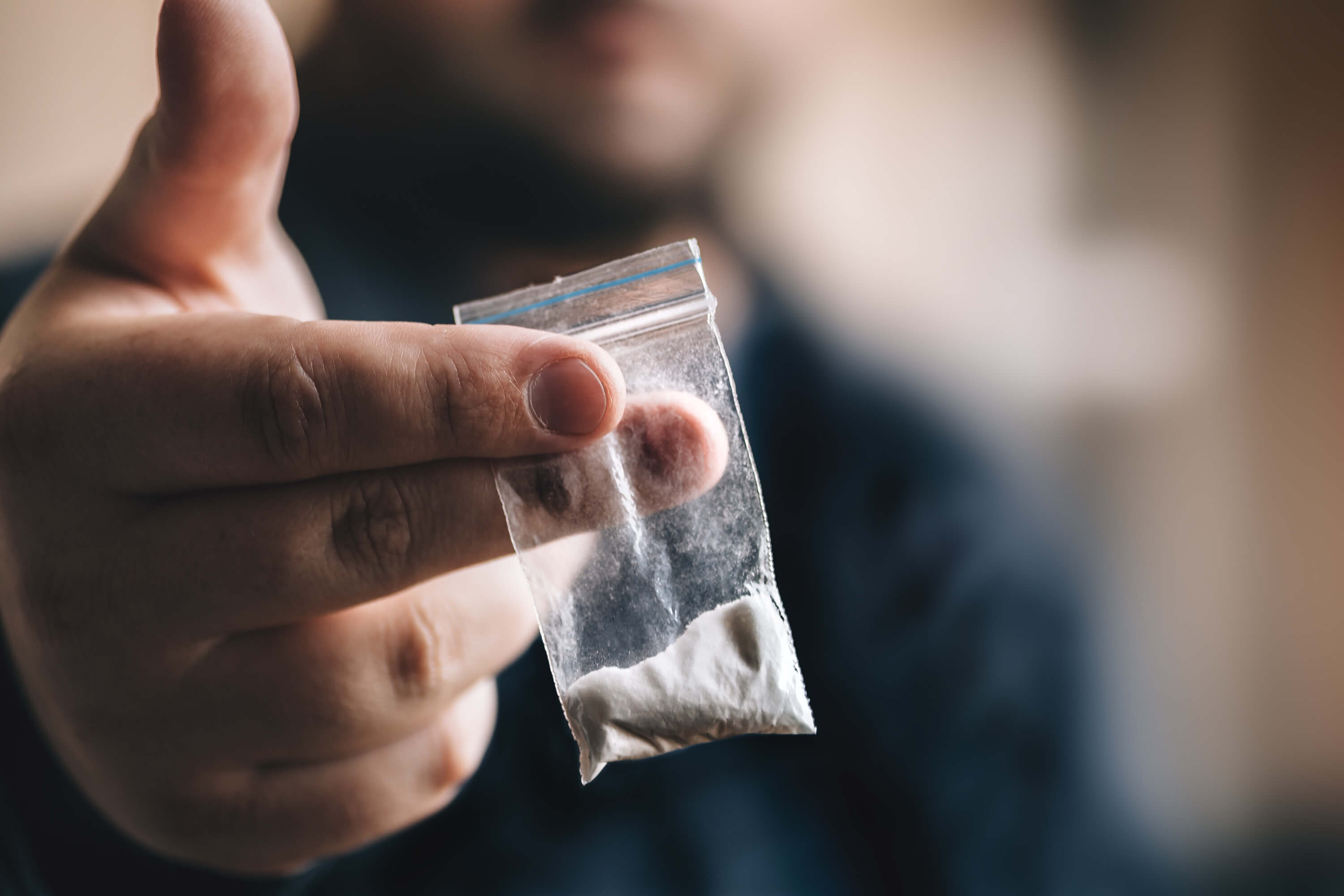 man holding a small packet of cocaine